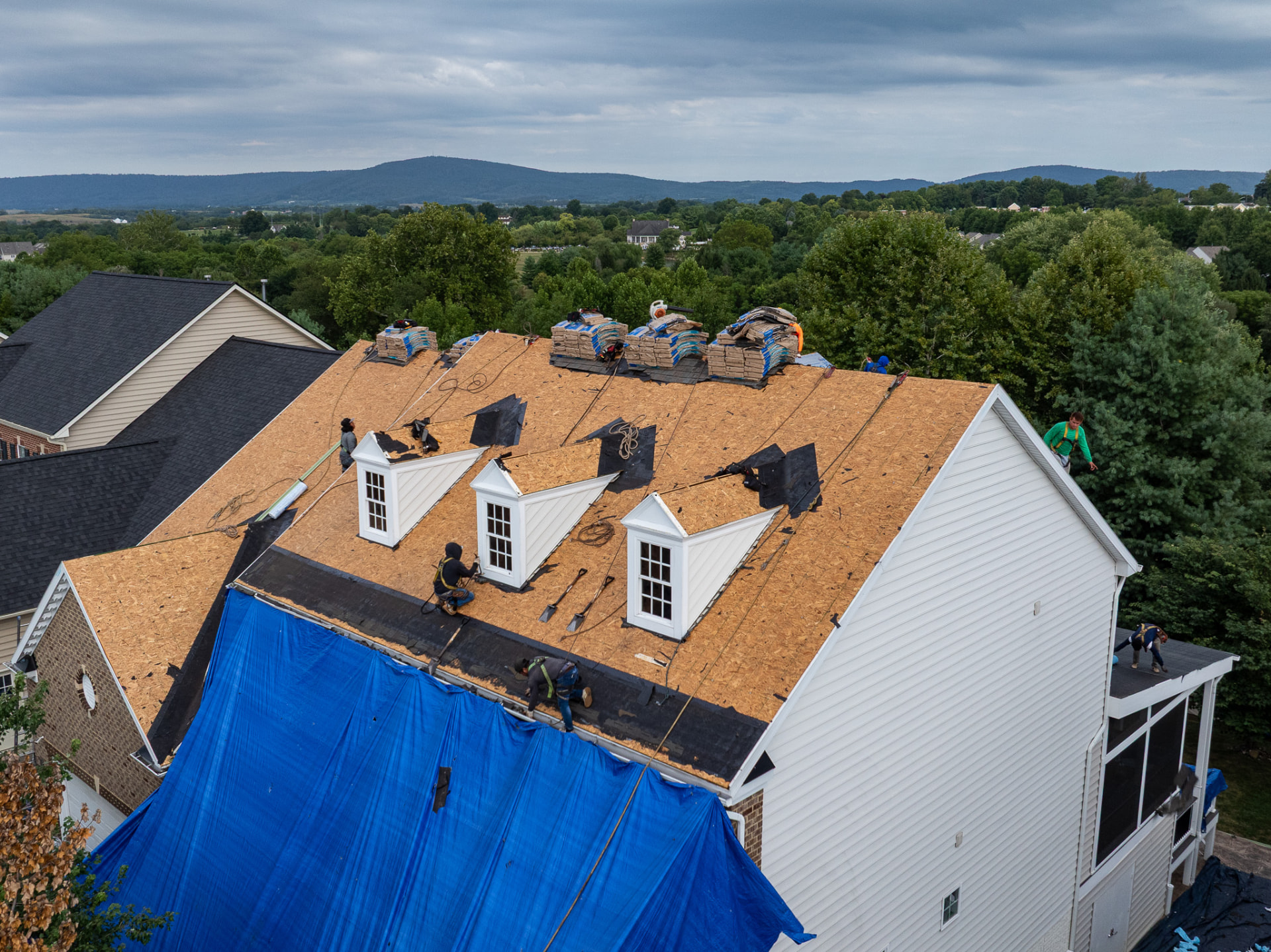 Aerial view of a roofing crew replacing a residential roof
